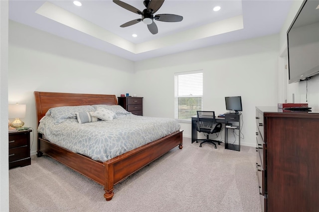 bedroom featuring ceiling fan, a tray ceiling, and light carpet