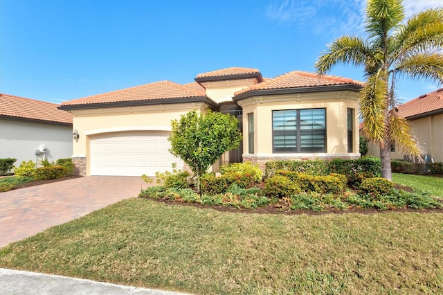 mediterranean / spanish-style home with decorative driveway, stucco siding, a front yard, a garage, and stone siding