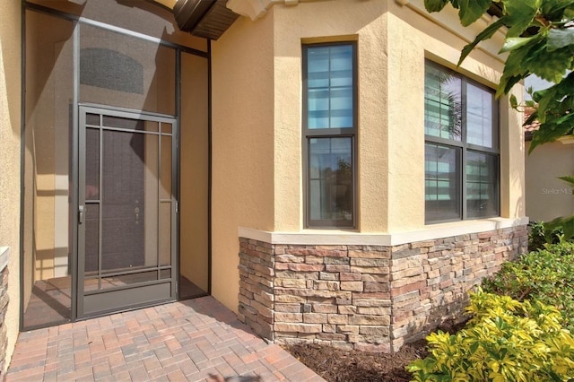 entrance to property featuring stone siding and stucco siding