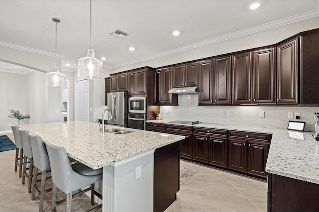 kitchen with sink, hanging light fixtures, stainless steel appliances, light stone countertops, and an island with sink