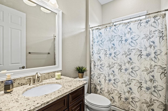 bathroom featuring toilet, a shower with curtain, a textured wall, and vanity