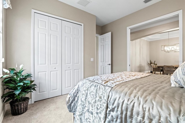 carpeted bedroom featuring a closet, visible vents, and an inviting chandelier