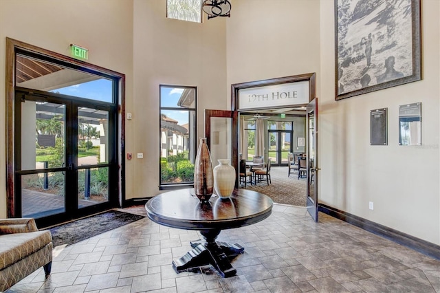 foyer with stone finish floor, a high ceiling, baseboards, and french doors