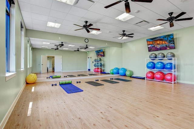 gym with a paneled ceiling, baseboards, and wood finished floors