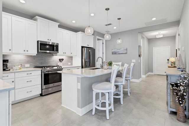 12488 Palatka Dr, Venice, FL 34293 - kitchen featuring sink, white cabinetry, appliances with stainless steel finishes, pendant lighting, and a kitchen island with sink