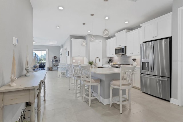 12488 Palatka Dr, Venice, FL 34293 - kitchen with a kitchen island with sink, decorative light fixtures, stainless steel appliances, and white cabinets