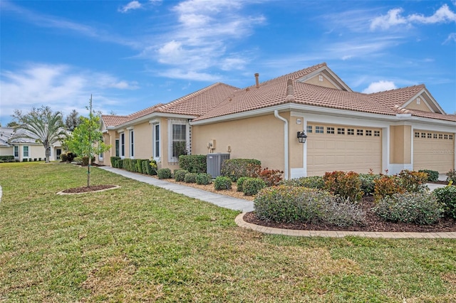 view of side of home with a garage, cooling unit, and a lawn