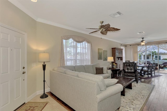 living room with light hardwood / wood-style floors, ornamental molding, ceiling fan, and a healthy amount of sunlight