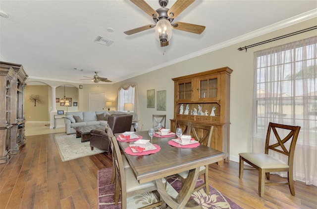 dining room with ceiling fan, dark hardwood / wood-style flooring, crown molding, and ornate columns