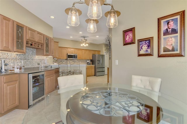 kitchen featuring ceiling fan, stainless steel appliances, decorative backsplash, beverage cooler, and hanging light fixtures