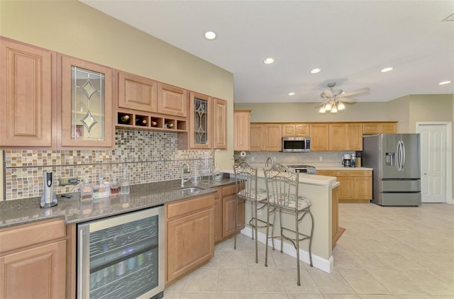 kitchen with wine cooler, decorative backsplash, sink, a kitchen breakfast bar, and stainless steel appliances