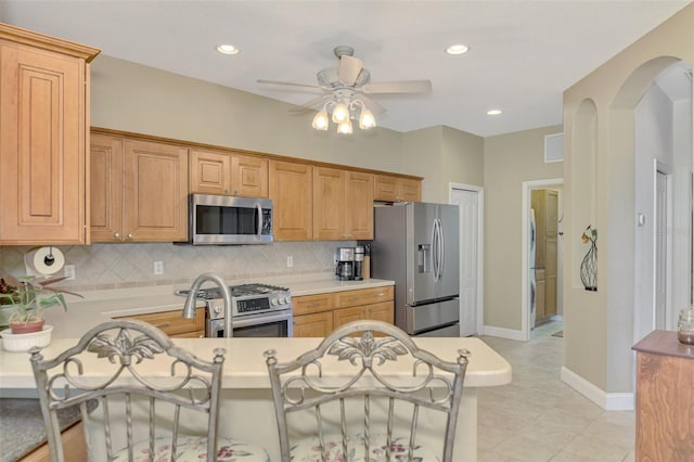 kitchen with tasteful backsplash, kitchen peninsula, stainless steel appliances, and ceiling fan