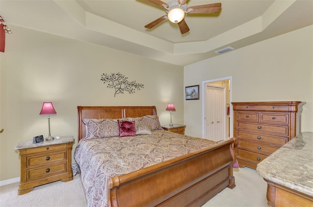 carpeted bedroom with a raised ceiling, ceiling fan, and a closet