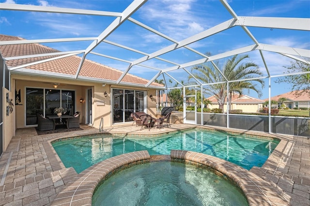 view of pool with an in ground hot tub, a patio area, and glass enclosure