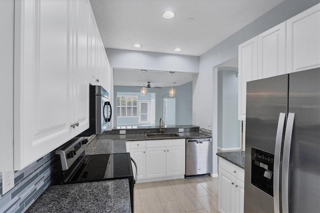 kitchen with hanging light fixtures, appliances with stainless steel finishes, sink, white cabinets, and dark stone counters