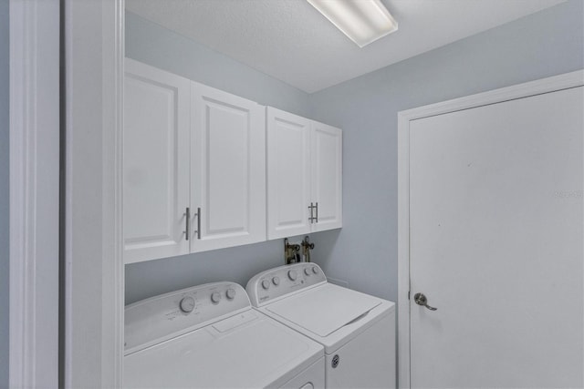 laundry room featuring separate washer and dryer, a textured ceiling, and cabinets