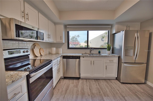 kitchen with light stone countertops, sink, white cabinetry, and appliances with stainless steel finishes