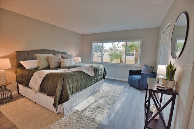 bedroom with light wood-type flooring and a textured ceiling