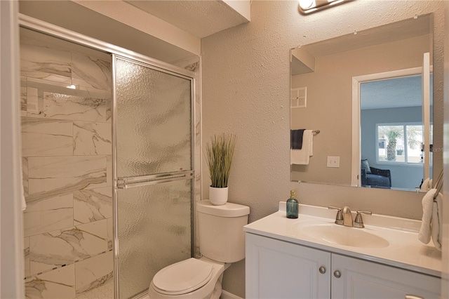 bathroom featuring toilet, a textured ceiling, a shower with shower door, and vanity