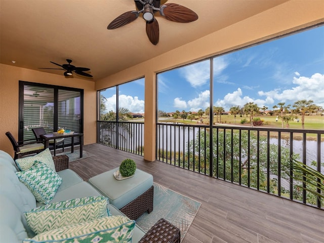 sunroom / solarium featuring ceiling fan and a water view