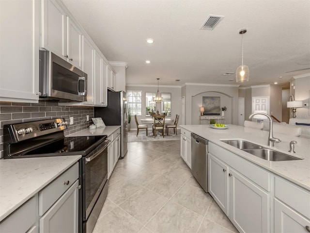 kitchen with hanging light fixtures, white cabinetry, appliances with stainless steel finishes, and sink