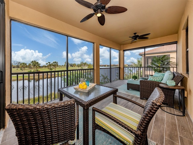 sunroom / solarium with a water view and ceiling fan