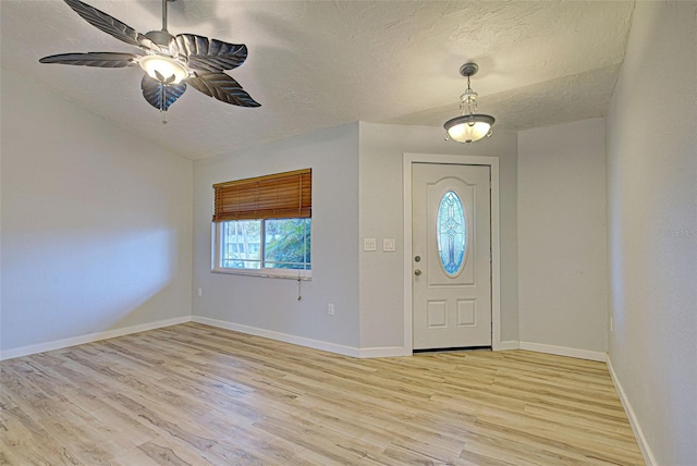 foyer with ceiling fan, light hardwood / wood-style flooring, and a textured ceiling