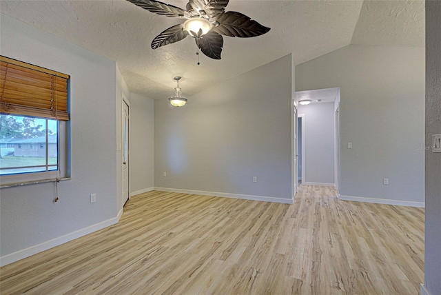 empty room featuring vaulted ceiling, ceiling fan, a textured ceiling, and light wood-type flooring