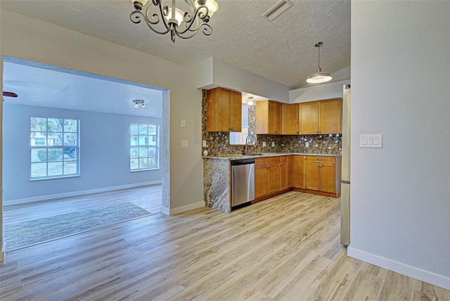 kitchen with tasteful backsplash, sink, hanging light fixtures, stainless steel dishwasher, and light wood-type flooring