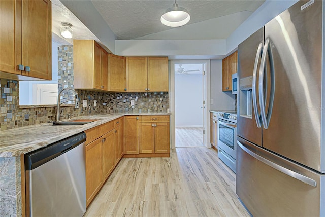 kitchen featuring sink, a textured ceiling, stainless steel appliances, light hardwood / wood-style floors, and backsplash