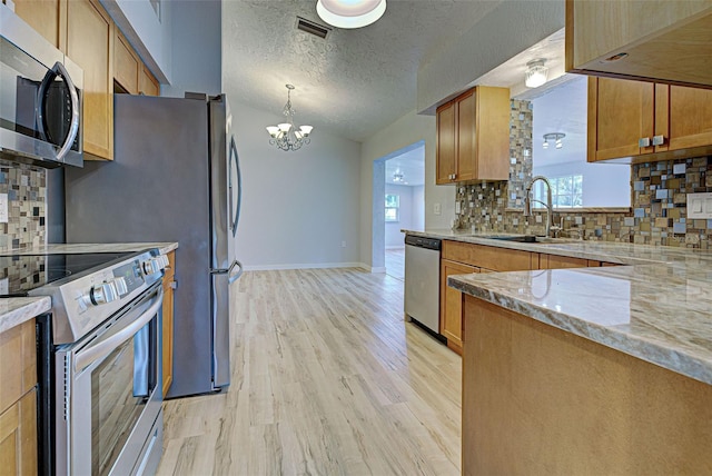 kitchen featuring sink, light wood-type flooring, backsplash, stainless steel appliances, and a textured ceiling