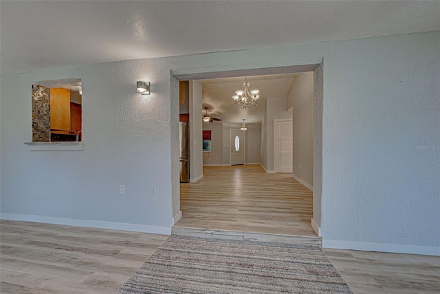 hallway featuring an inviting chandelier and light hardwood / wood-style flooring