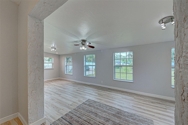 empty room featuring vaulted ceiling, plenty of natural light, a textured ceiling, and light hardwood / wood-style floors