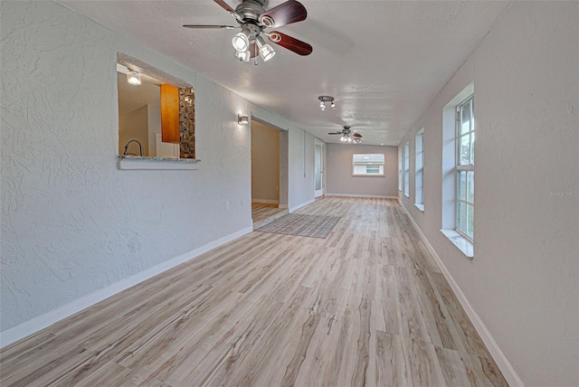 unfurnished living room featuring ceiling fan, a textured ceiling, and light hardwood / wood-style floors