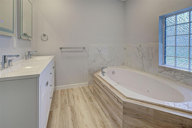 bathroom with hardwood / wood-style floors, vanity, and a relaxing tiled tub