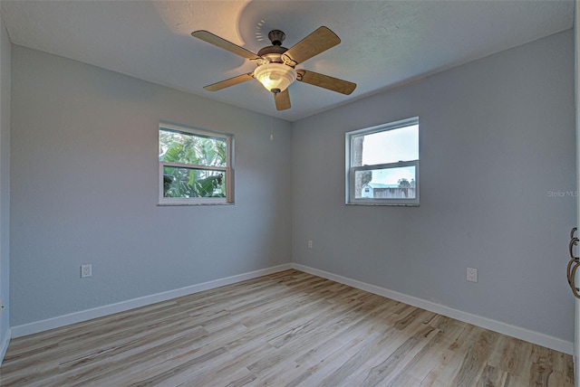 spare room featuring ceiling fan, a healthy amount of sunlight, and light wood-type flooring