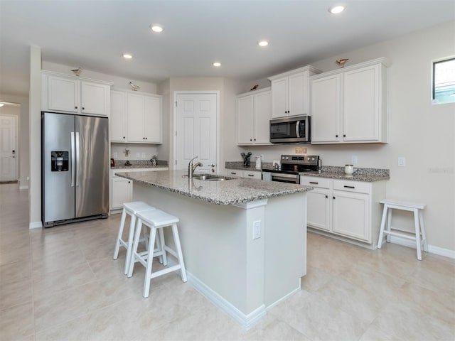 kitchen with white cabinetry, a kitchen bar, a center island with sink, stainless steel appliances, and sink