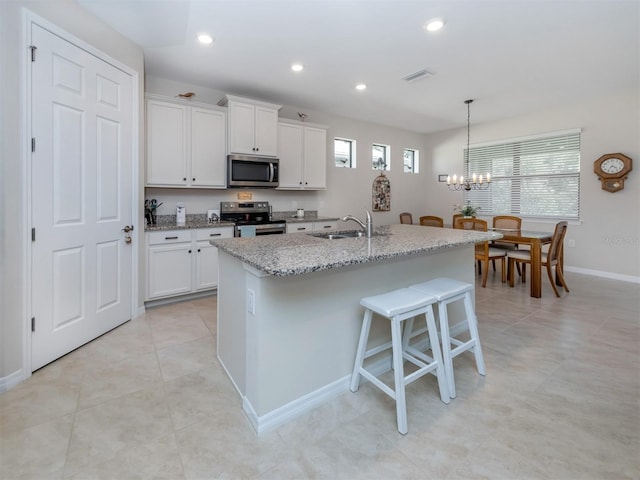 kitchen with sink, white cabinetry, appliances with stainless steel finishes, and an island with sink