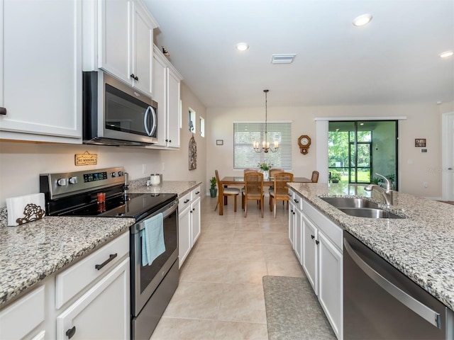 kitchen featuring light tile patterned floors, appliances with stainless steel finishes, white cabinets, light stone counters, and sink