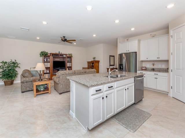 kitchen with stainless steel appliances, sink, white cabinetry, and a kitchen island with sink