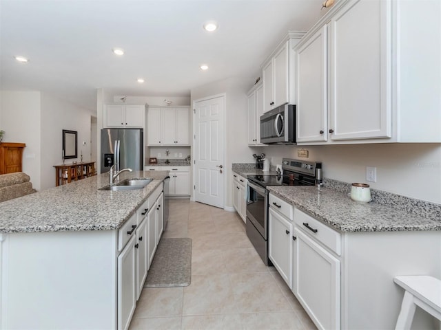 kitchen featuring light stone countertops, white cabinets, appliances with stainless steel finishes, sink, and light tile patterned floors