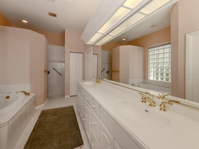 bathroom with tile patterned flooring, vanity, and tiled bath