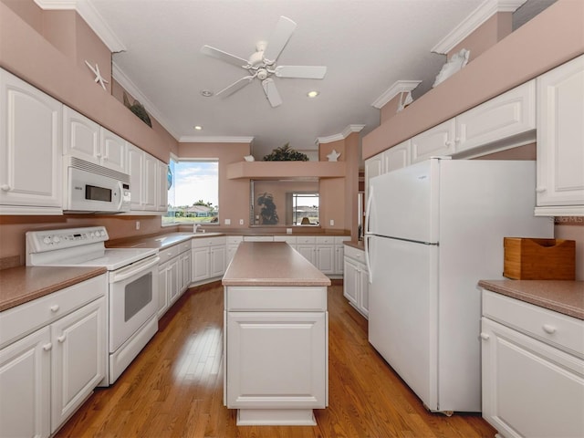 kitchen with ornamental molding, a kitchen island, white appliances, light hardwood / wood-style floors, and white cabinets