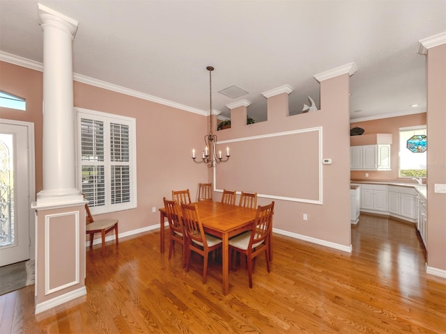 dining space with crown molding, light wood-type flooring, a chandelier, and ornate columns