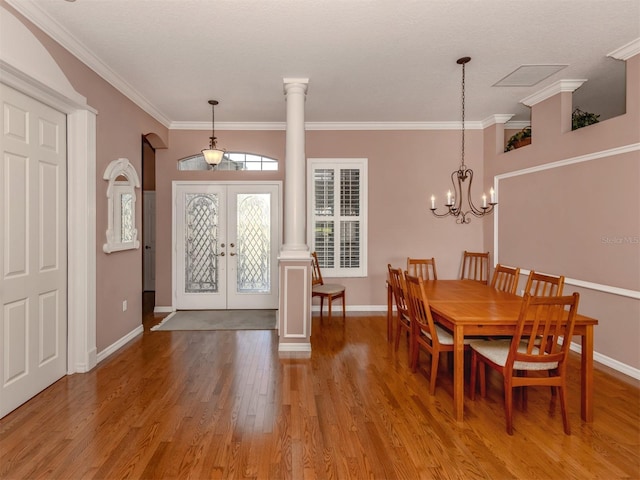 dining area featuring french doors, wood-type flooring, crown molding, and ornate columns