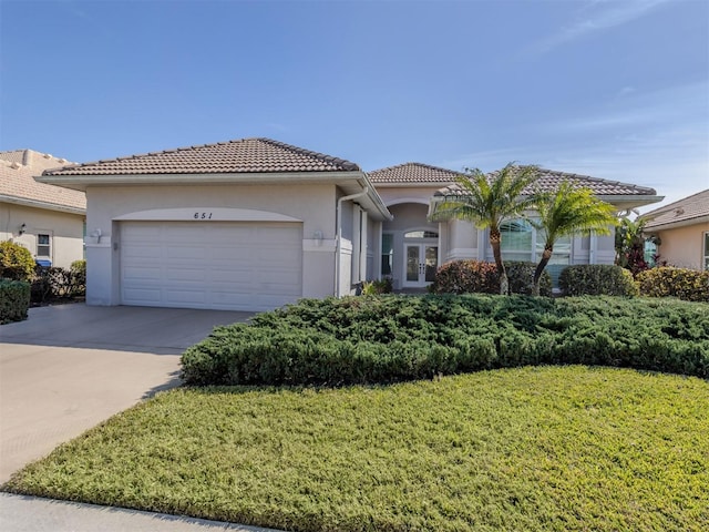 mediterranean / spanish-style house featuring a garage and a front yard