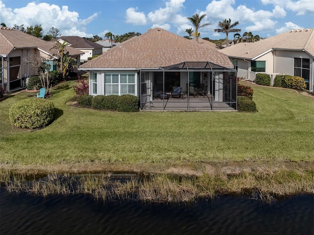 back of house with a water view, a yard, and a lanai