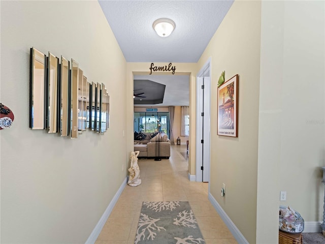 hall featuring a textured ceiling and light tile patterned flooring