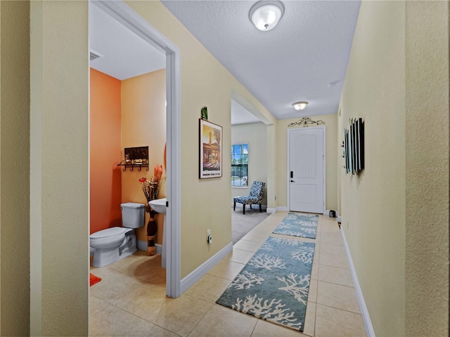 hallway featuring a textured ceiling and light tile patterned floors