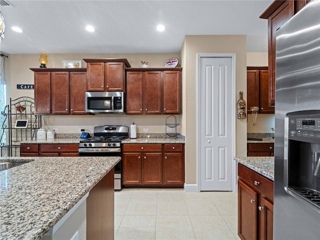 kitchen with light stone counters, light tile patterned flooring, and appliances with stainless steel finishes